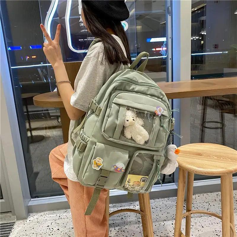 Light green mini backpack with multiple front compartments and plush animal inside