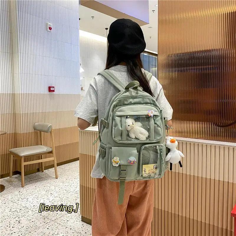 Mint green backpack with front compartments and plush animal in the clear window pocket