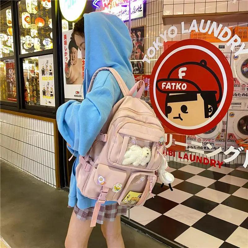 Light pink nylon mini backpack with front pockets, cartoon badges, plush bear and duck charm