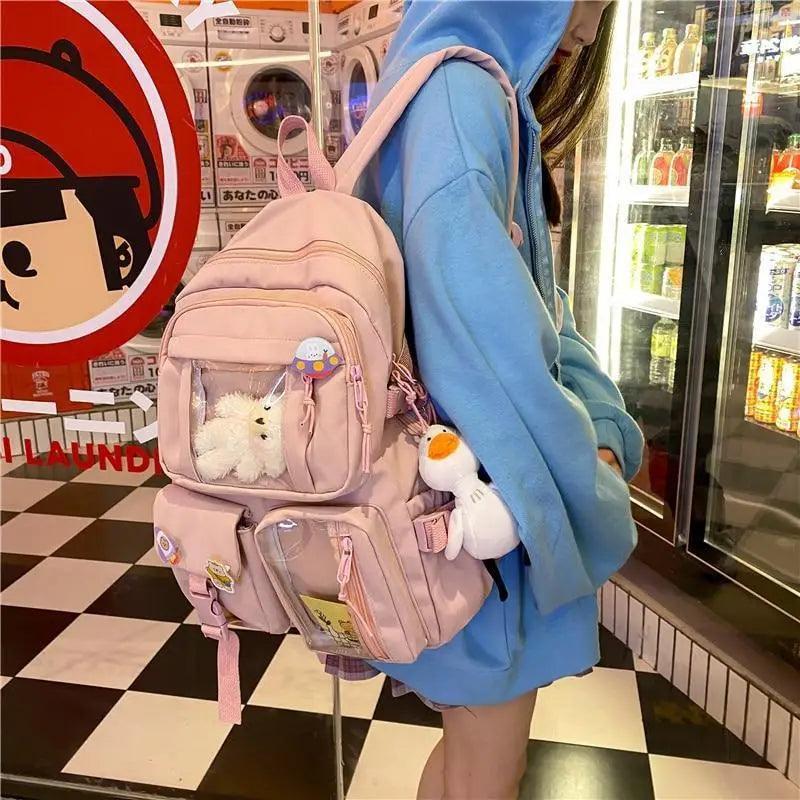 Pink nylon backpack with multiple front compartments and plush duck keychain