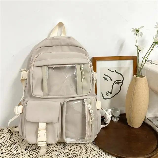 Beige nylon backpack with clear front pouch and multiple zippered compartments
