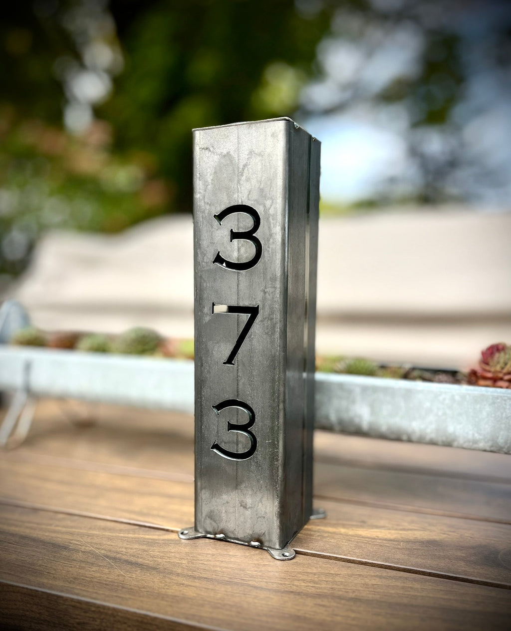 Steel solar address pillar light with numbers 3, 7, 3 engraved on a tall post