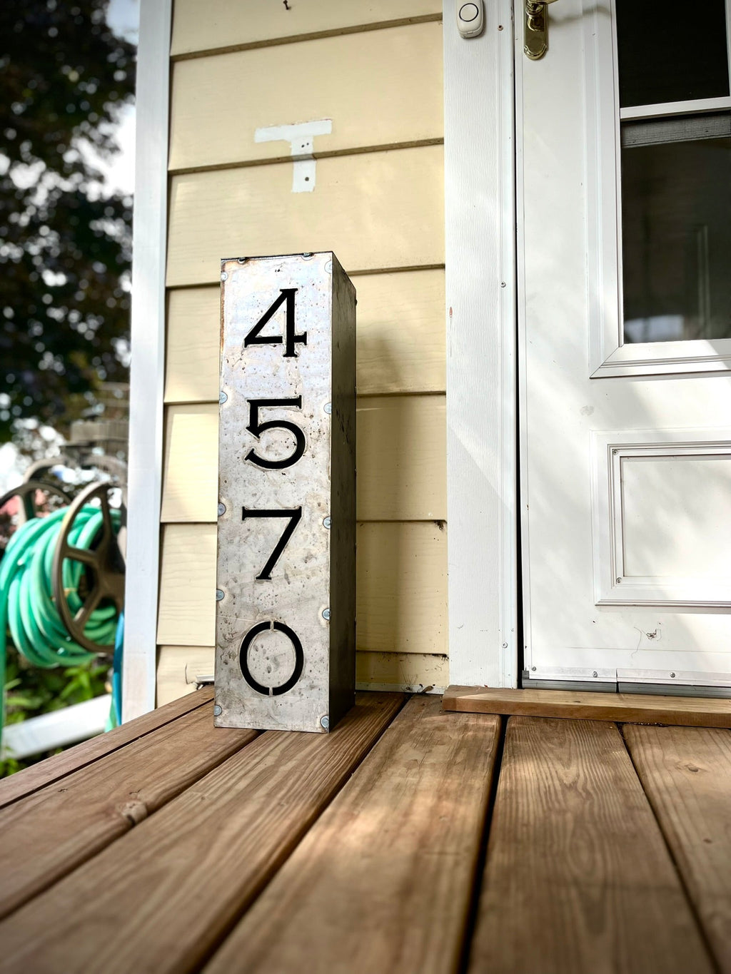 Steel solar address pillar light on a porch deck with numbers 4, 5, 7, 0