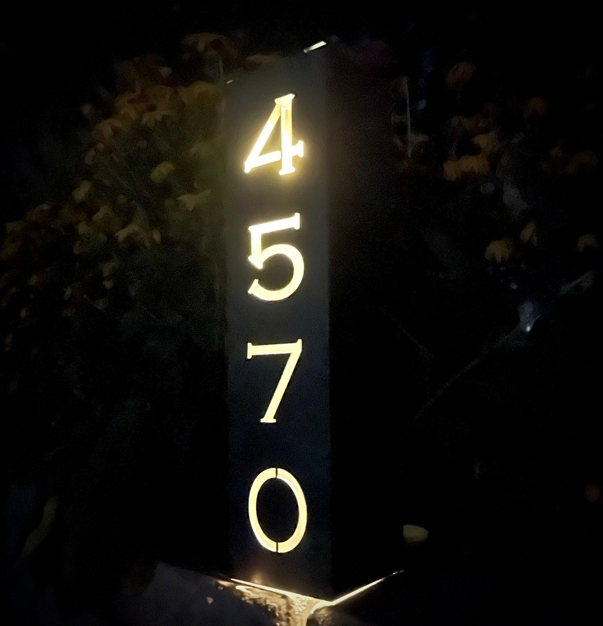 Solar address pillar light with glowing numbers 4, 5, 7 and 0 on a steel post