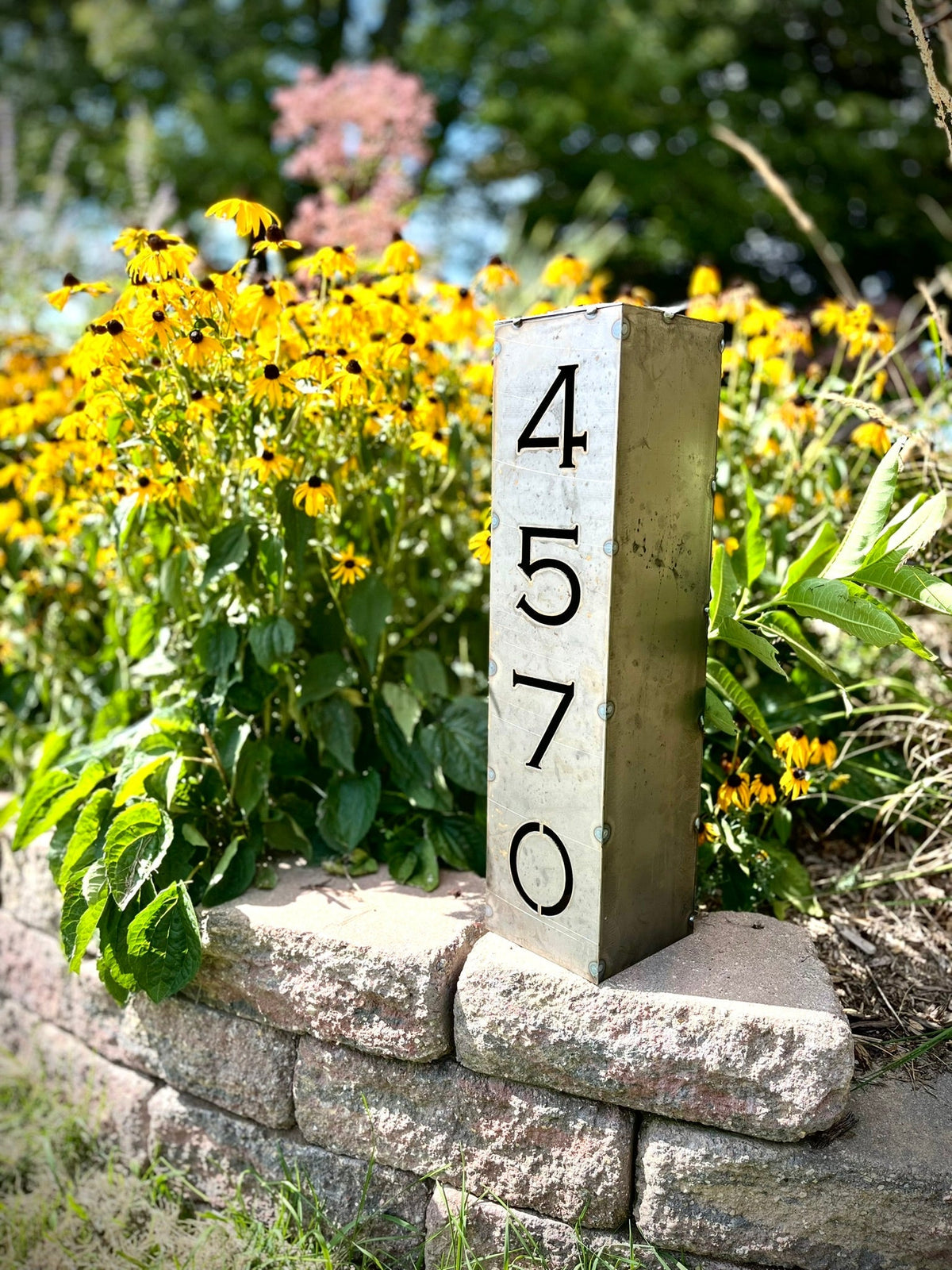 Steel solar address pillar light standing on stone wall with numbers 4, 5, 7, 6