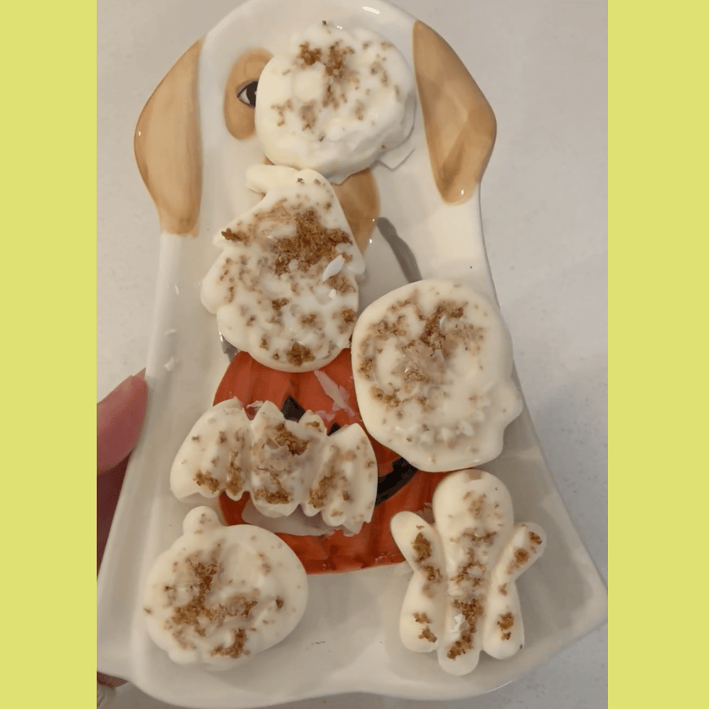Paw-shaped dog treats on a white platter with dark speckled tops