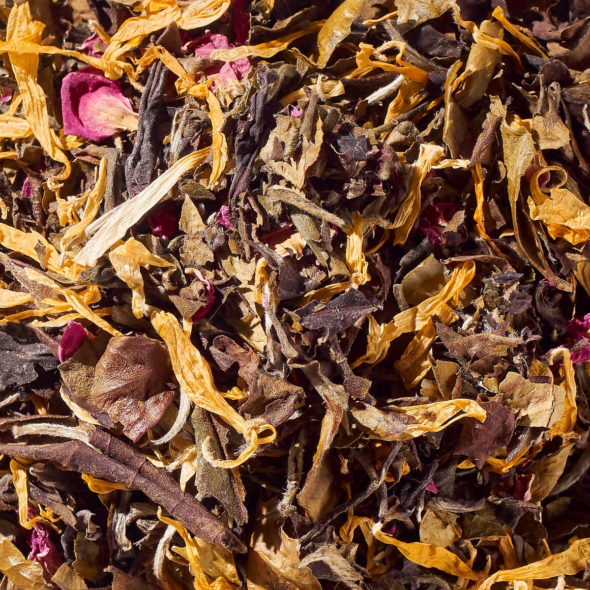 Close-up of loose white tea leaves with rose petals and golden calendula pieces