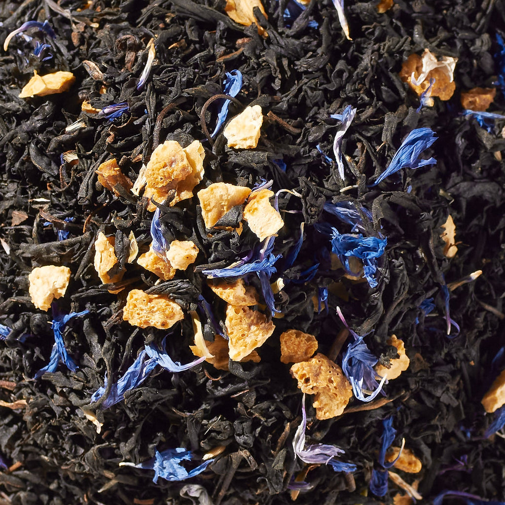Close-up of loose black tea leaves with orange peel and blue cornflower