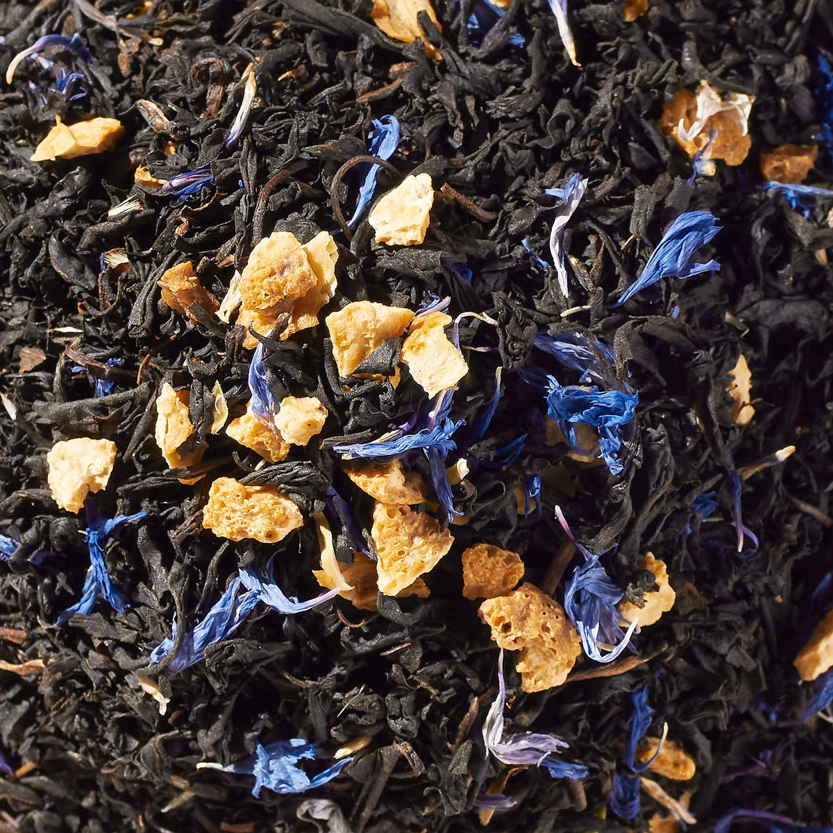 Close-up of loose black tea leaves with orange peel and blue cornflower