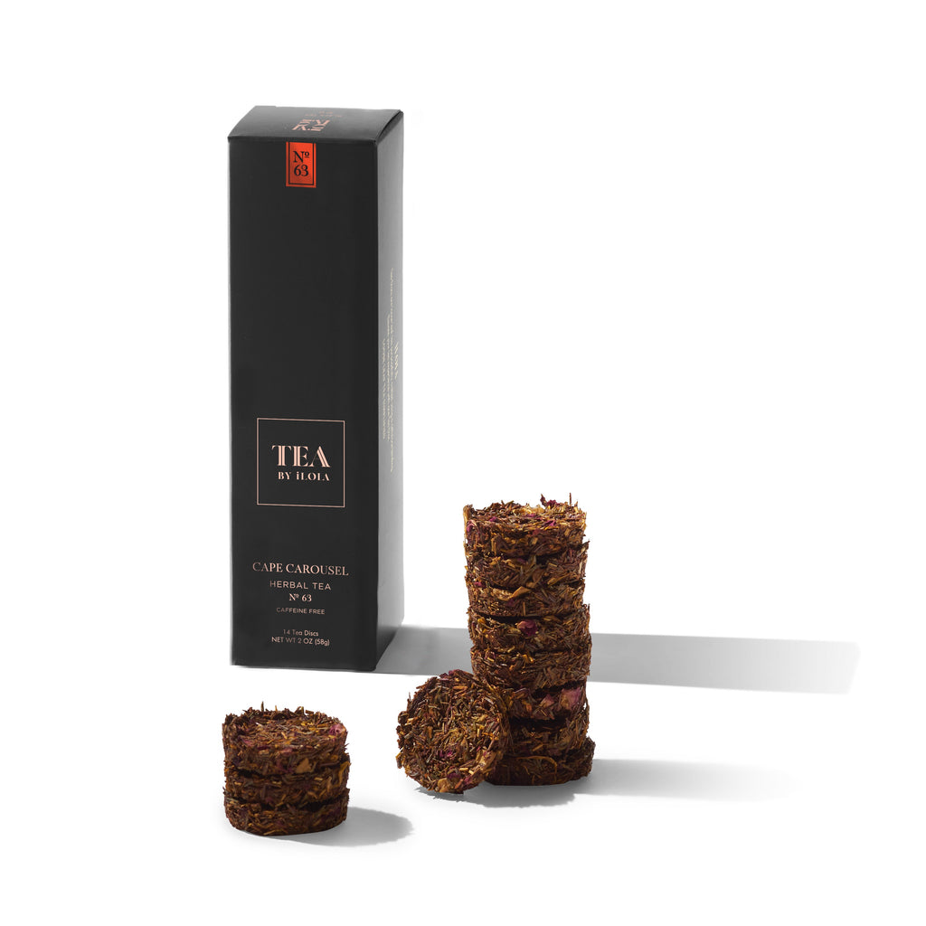Cape Carousel No. 63 herbal tea box beside stacked compressed tea discs