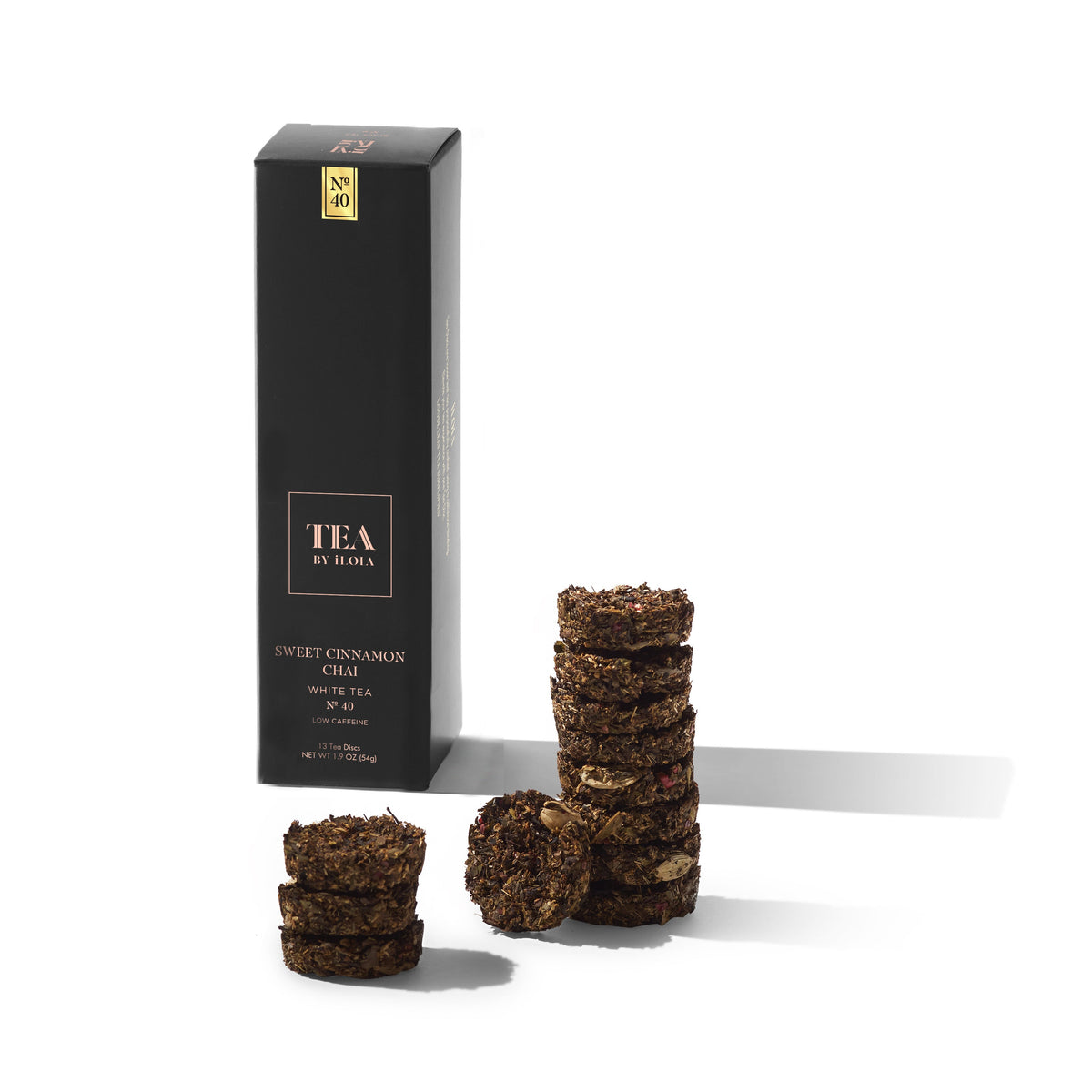 Sweet Cinnamon Chai tea box beside stacked and loose compressed tea discs.