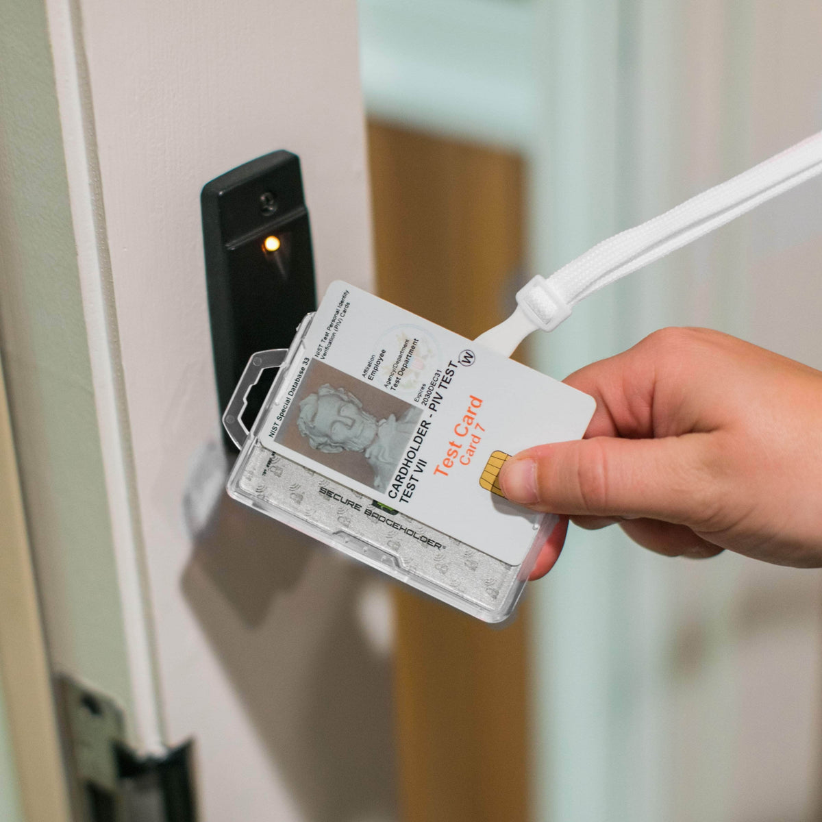Transparent card badge holder with two ID cards, held near a door access panel.