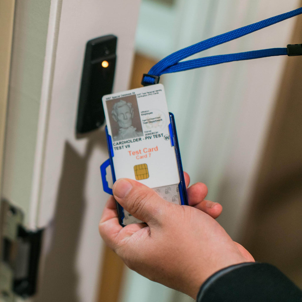 Blue badge holder on lanyard being held, with clear window and test ID card visible