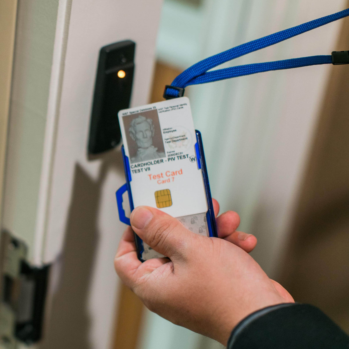 Blue badge holder on lanyard being held, with clear window and test ID card visible
