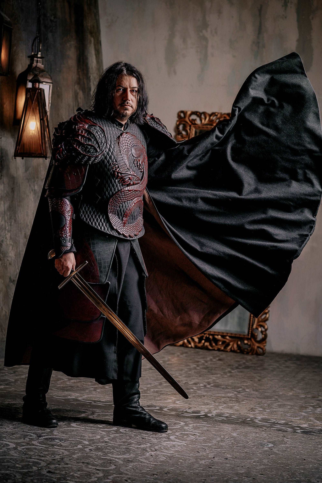 Vampire knight costume with flowing black cape and sword, posed near a wall