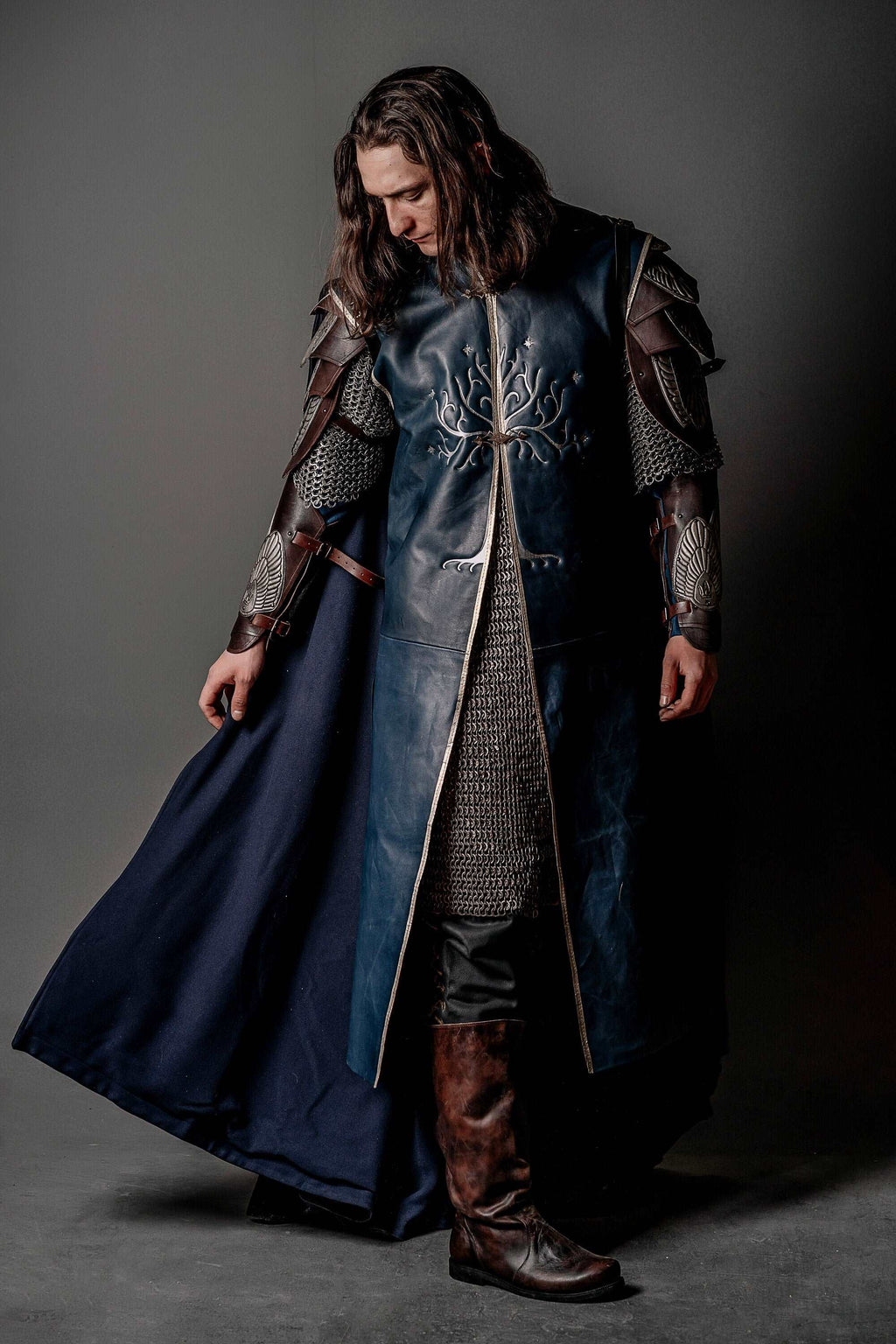 Long blue coat with silver tree embroidery, metal shoulder guards and dark cape