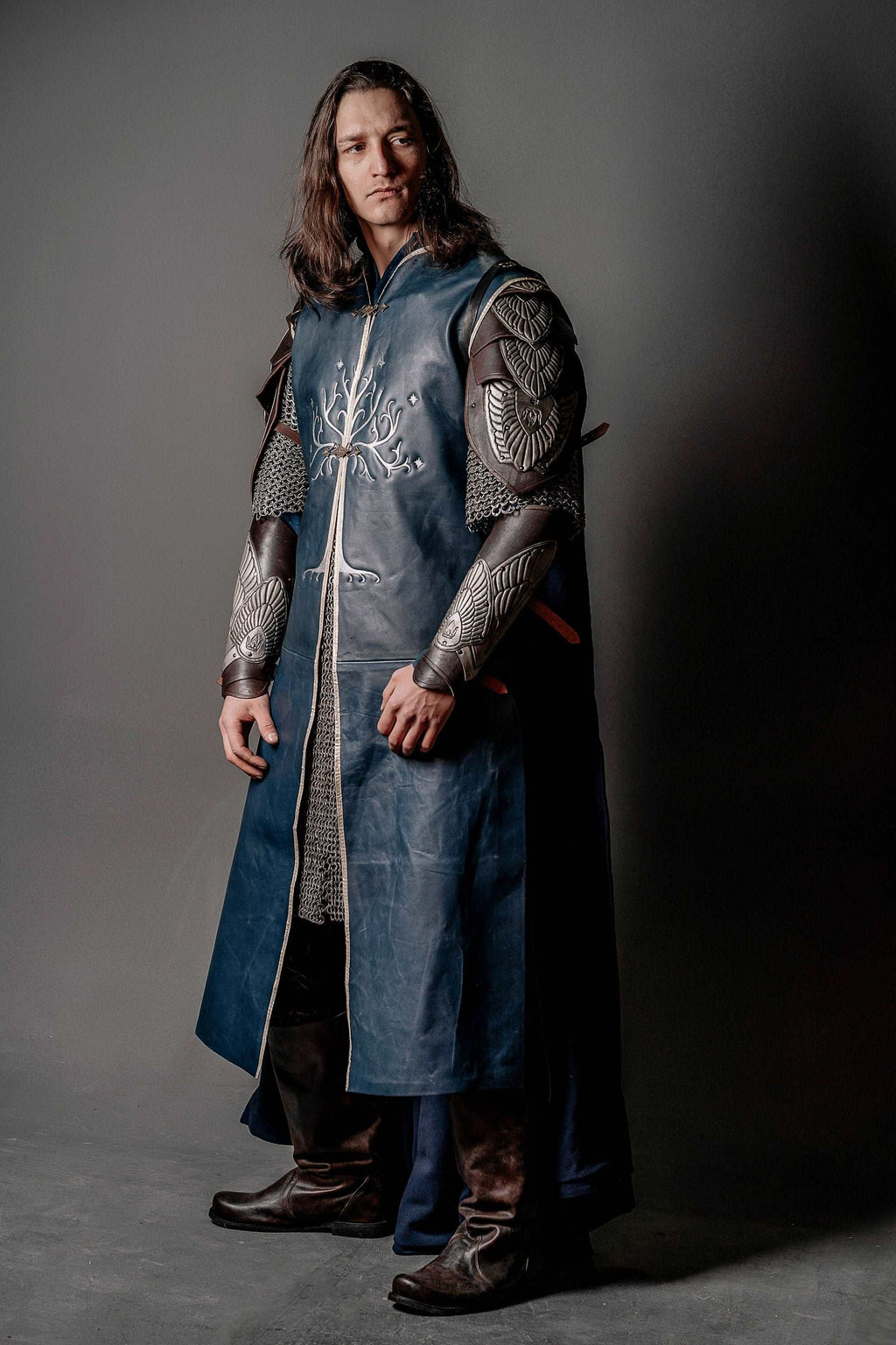 Blue embroidered tunic with plated arm guards and long dark outer cape