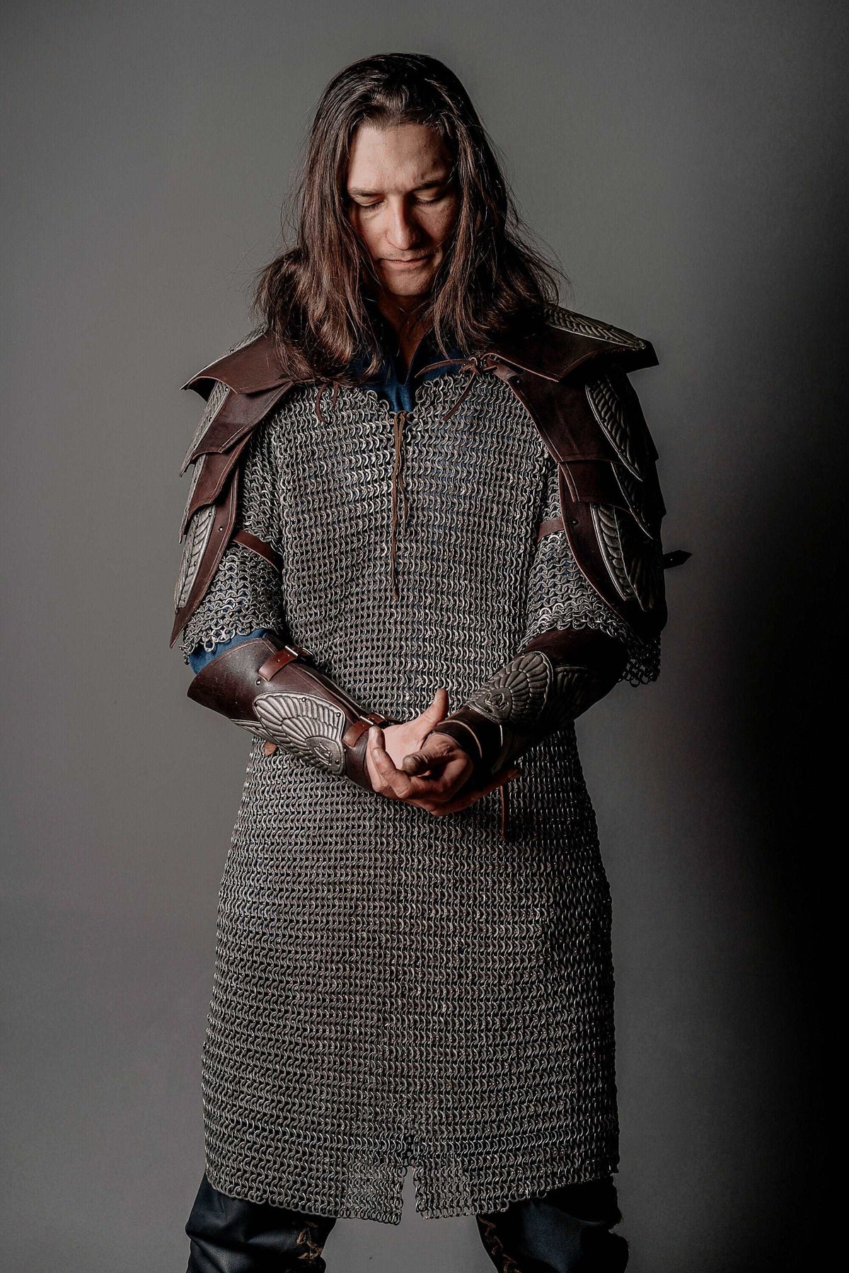 Gray chainmail-style tunic with brown shoulder armor and metal wrist bracers