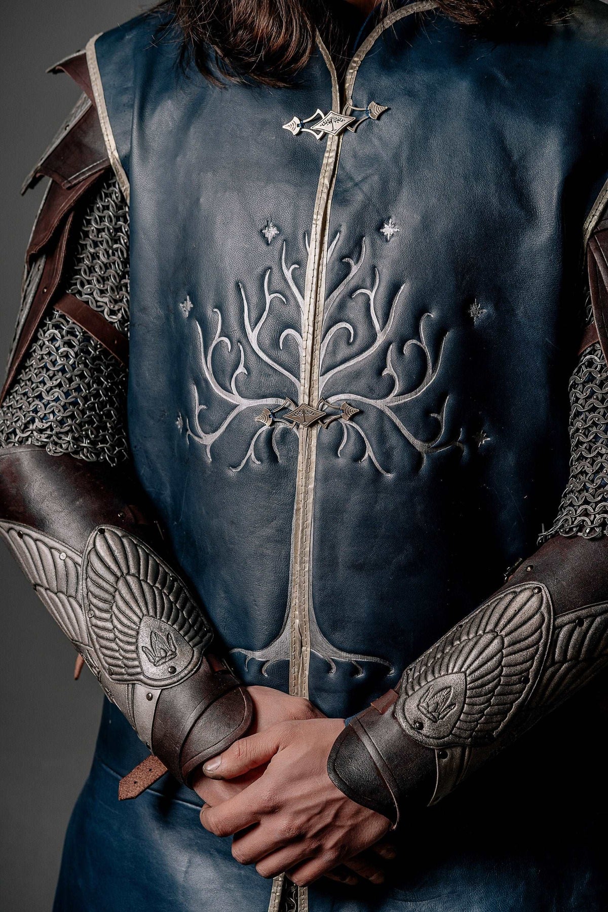 Close-up blue tunic front with silver tree embroidery and winged emblem details