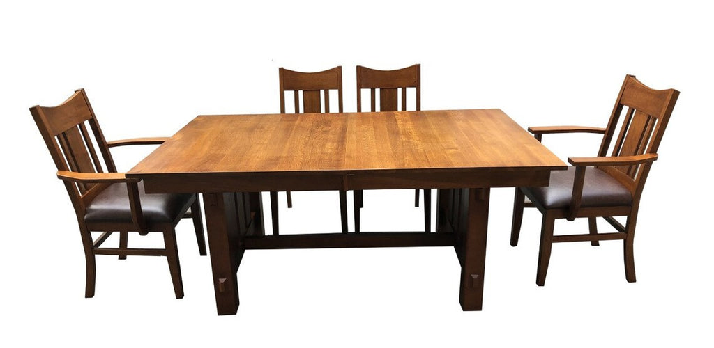 Rectangular wood dining table with four chairs and dark upholstered seat cushions.