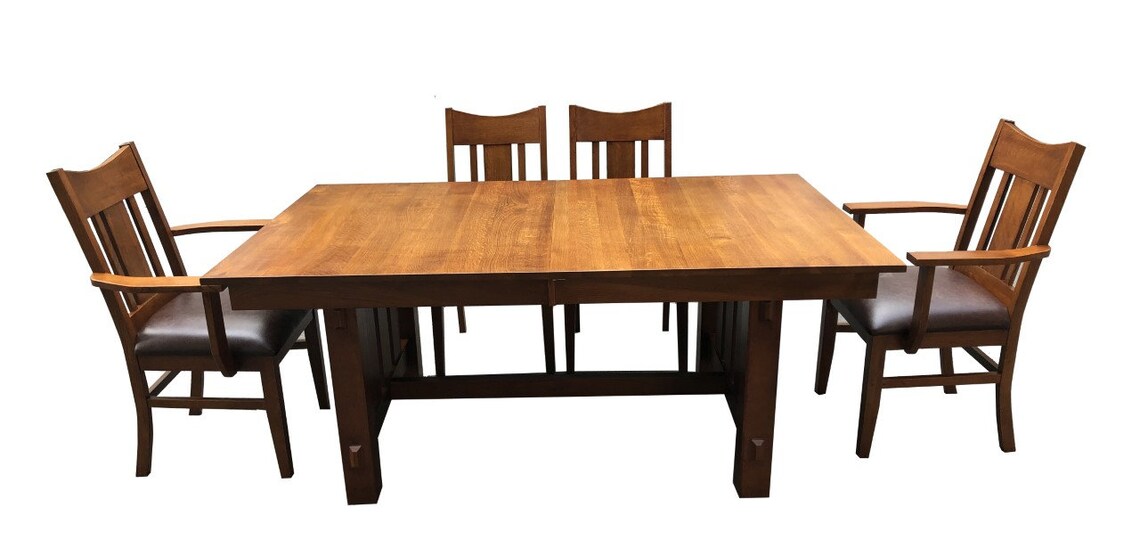 Rectangular wood dining table with four chairs and dark upholstered seat cushions.