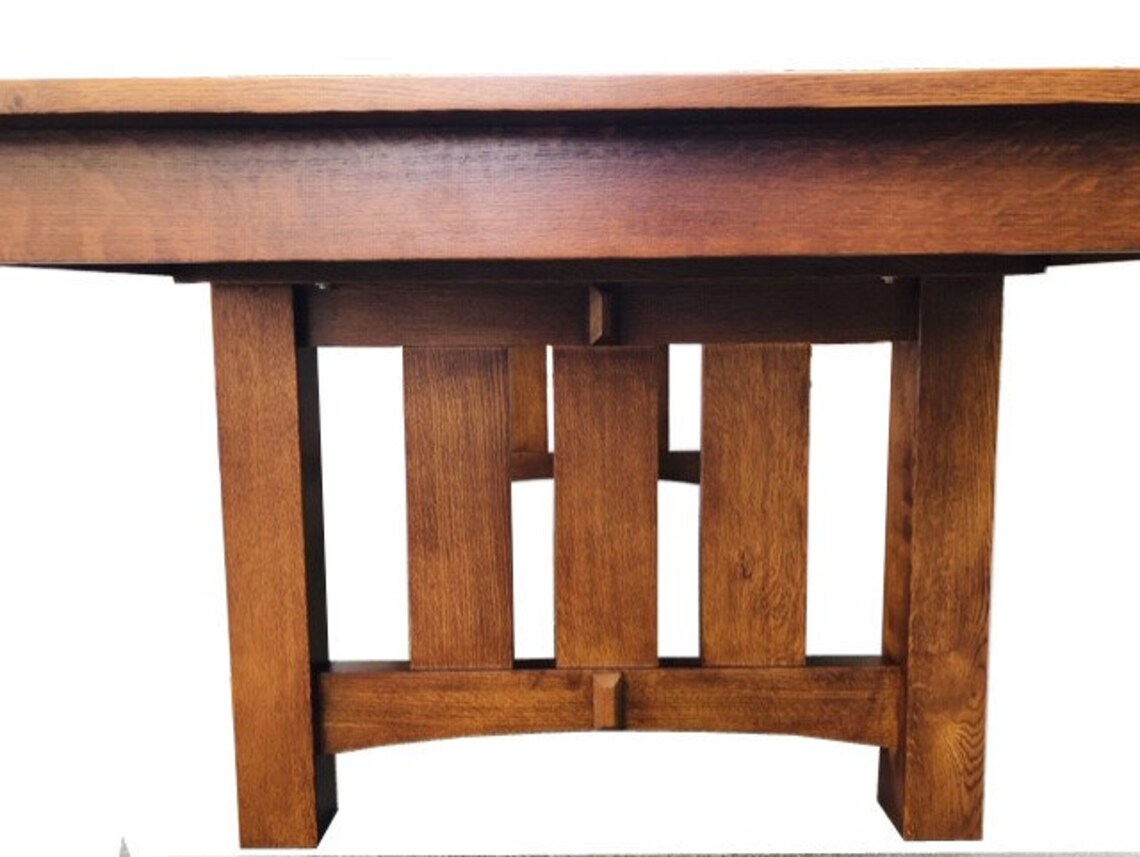 Dining table apron and leg view showing carved wood supports beneath tabletop.