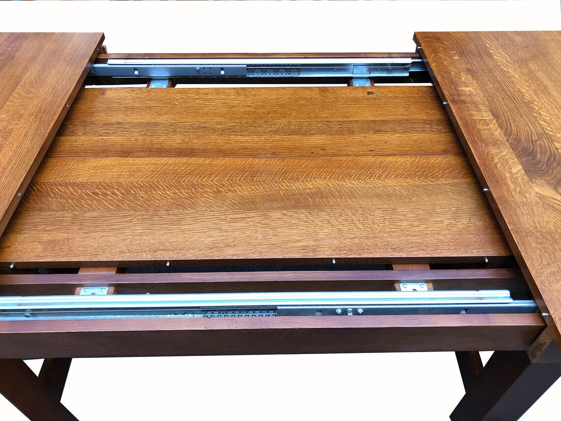 Wood dining table leaf and inner tracks detail with extended tabletop panels.