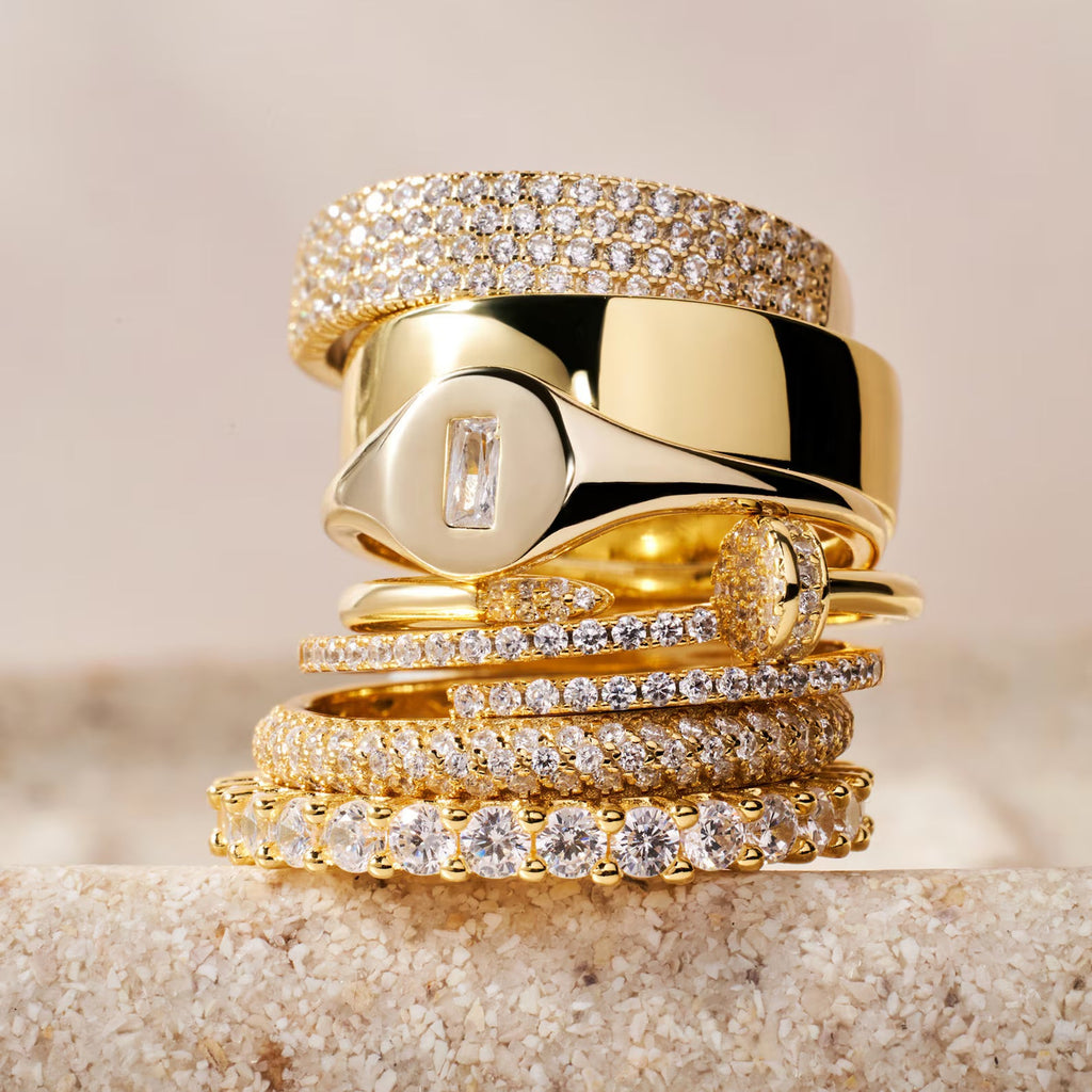 Gold eternity ring stack with multiple diamond-studded bands and one polished wide band