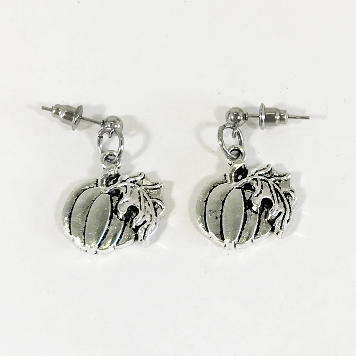 Silver-tone pumpkin dangle earrings with leaf stem and dangling charm details.