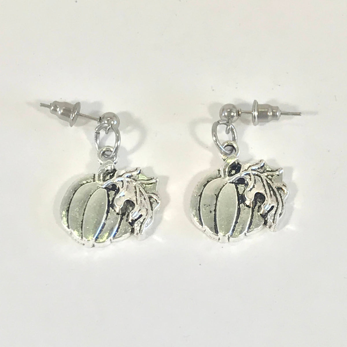 Silver-tone pumpkin charm earrings with circular posts and leaf stem detail.