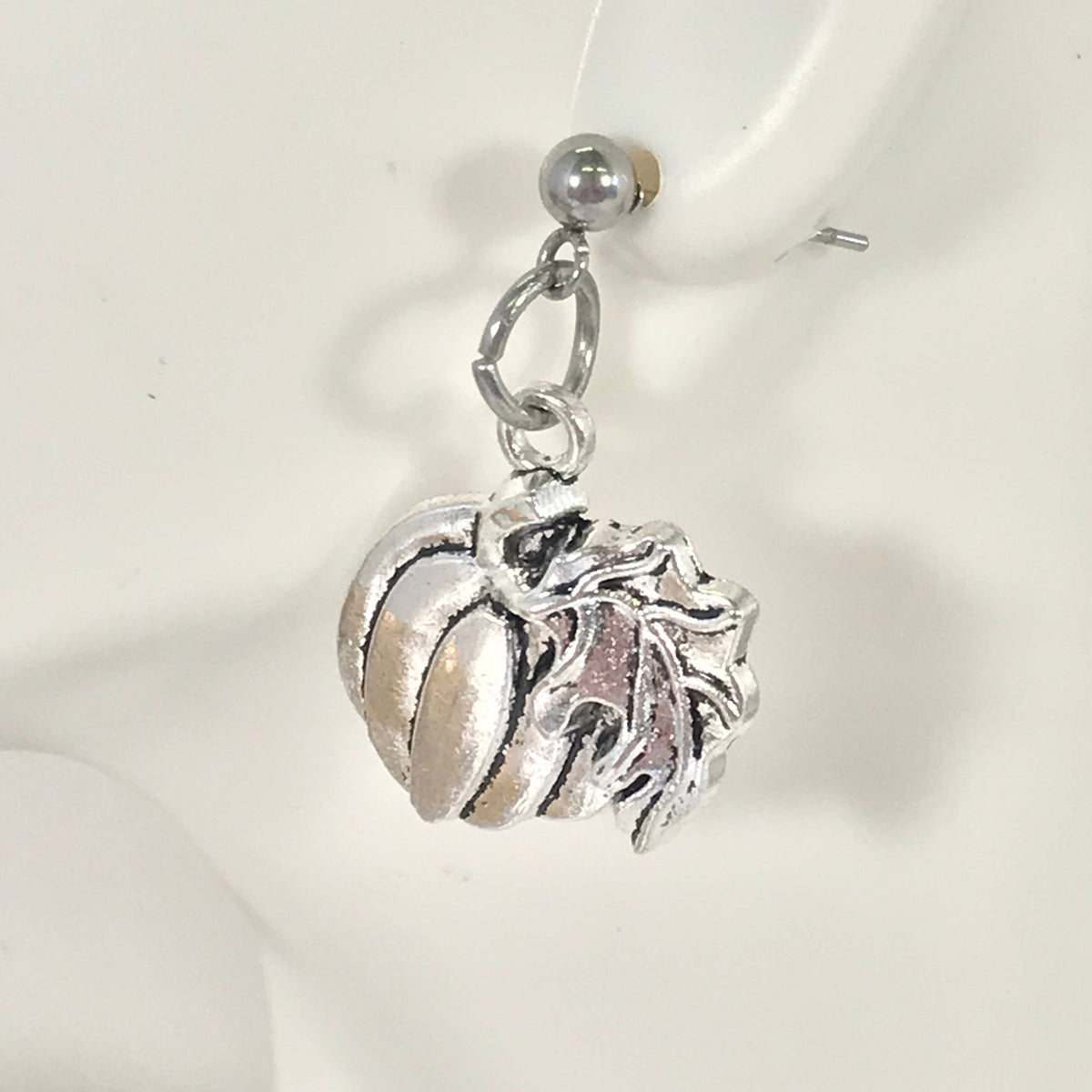 Silver-tone pumpkin charm earring close-up with hoop loop and leaf stem detail.