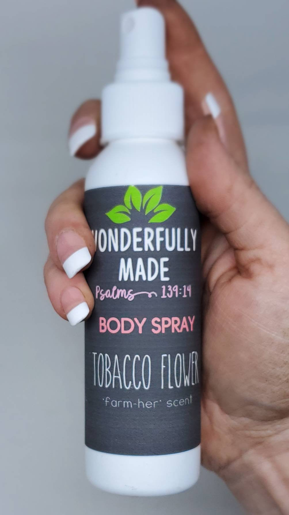 White body spray bottle with green leaf logo and dark blue tobacco flower label