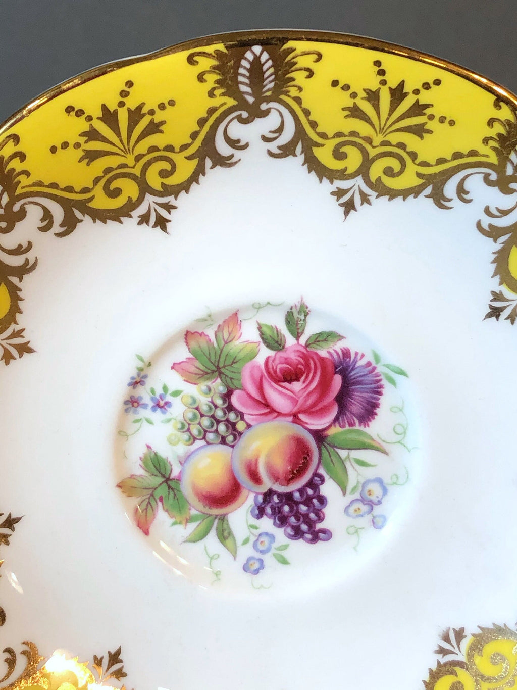 Close-up of yellow porcelain saucer top with floral fruit medallion centerpiece