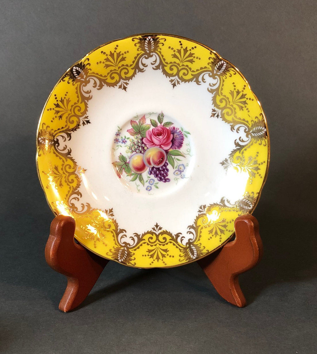 Decorative yellow and gold tea saucer with pink rose, grapes, and fruit medallion