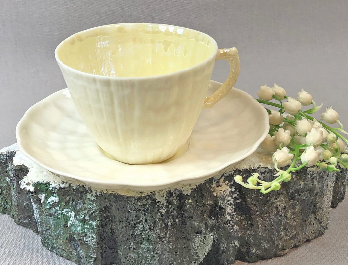 Porcelain cup and saucer set with seashell pattern, pale yellow glaze.