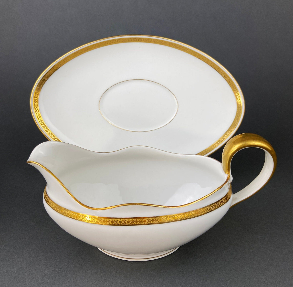 White porcelain gravy boat with gold-trimmed oval platter and thin gold ring border