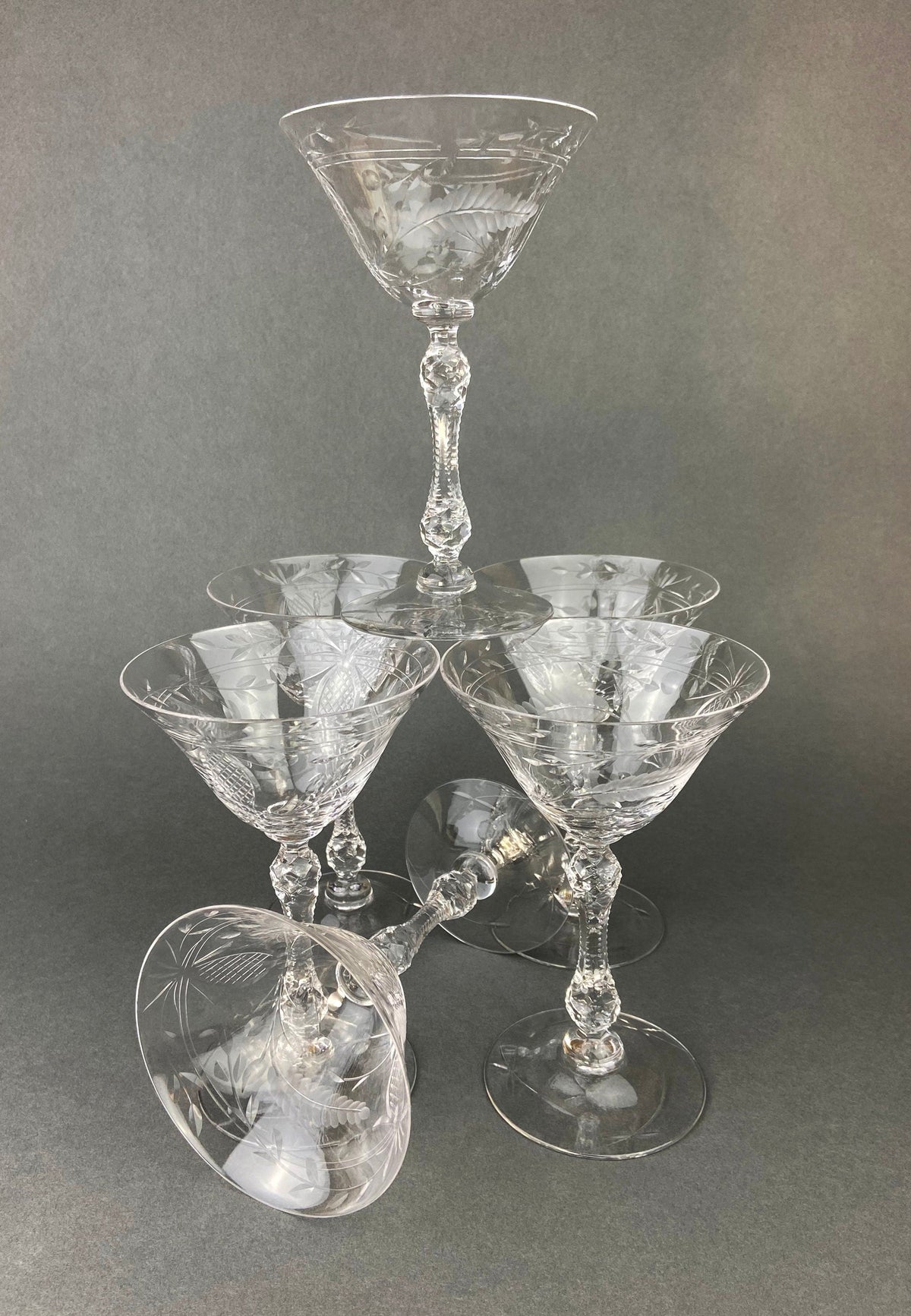 Group of cut crystal champagne glasses with faceted stems and patterned bowls