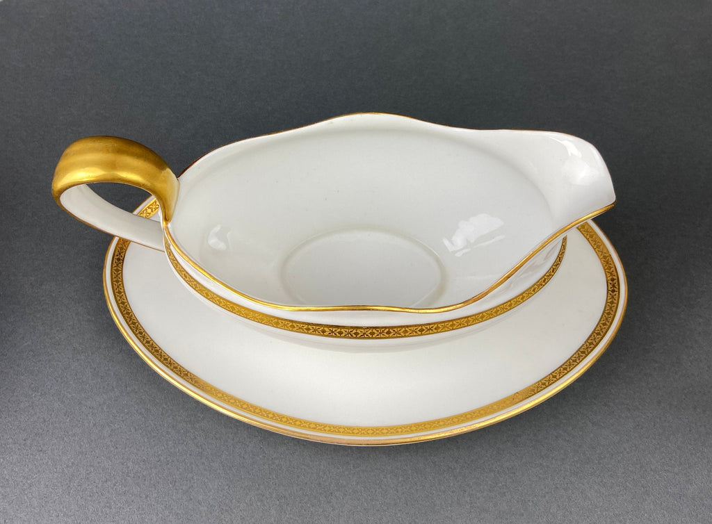 White porcelain soup boat with gold handle, scalloped rim, and decorative gold band