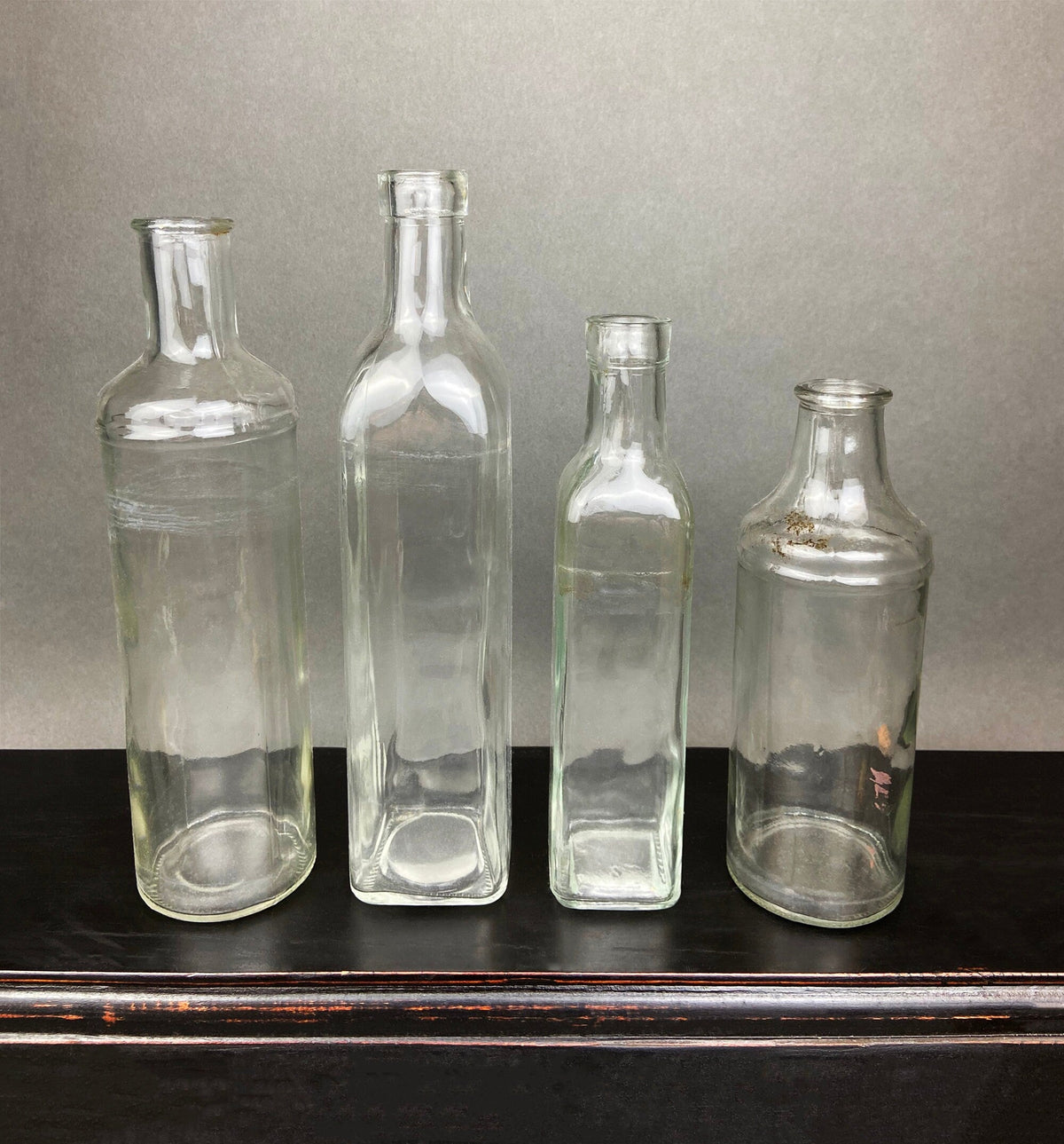 Four clear glass apothecary bottles standing side by side