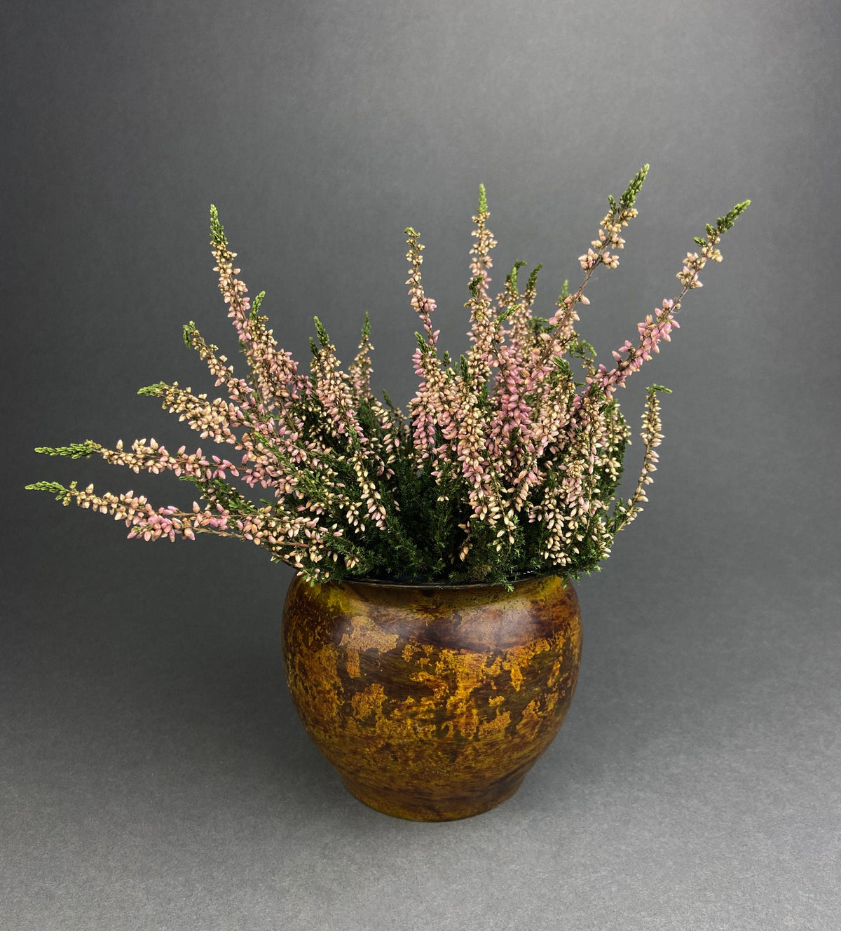 Hammered brass flower pot vase filled with small pink and green dried stems