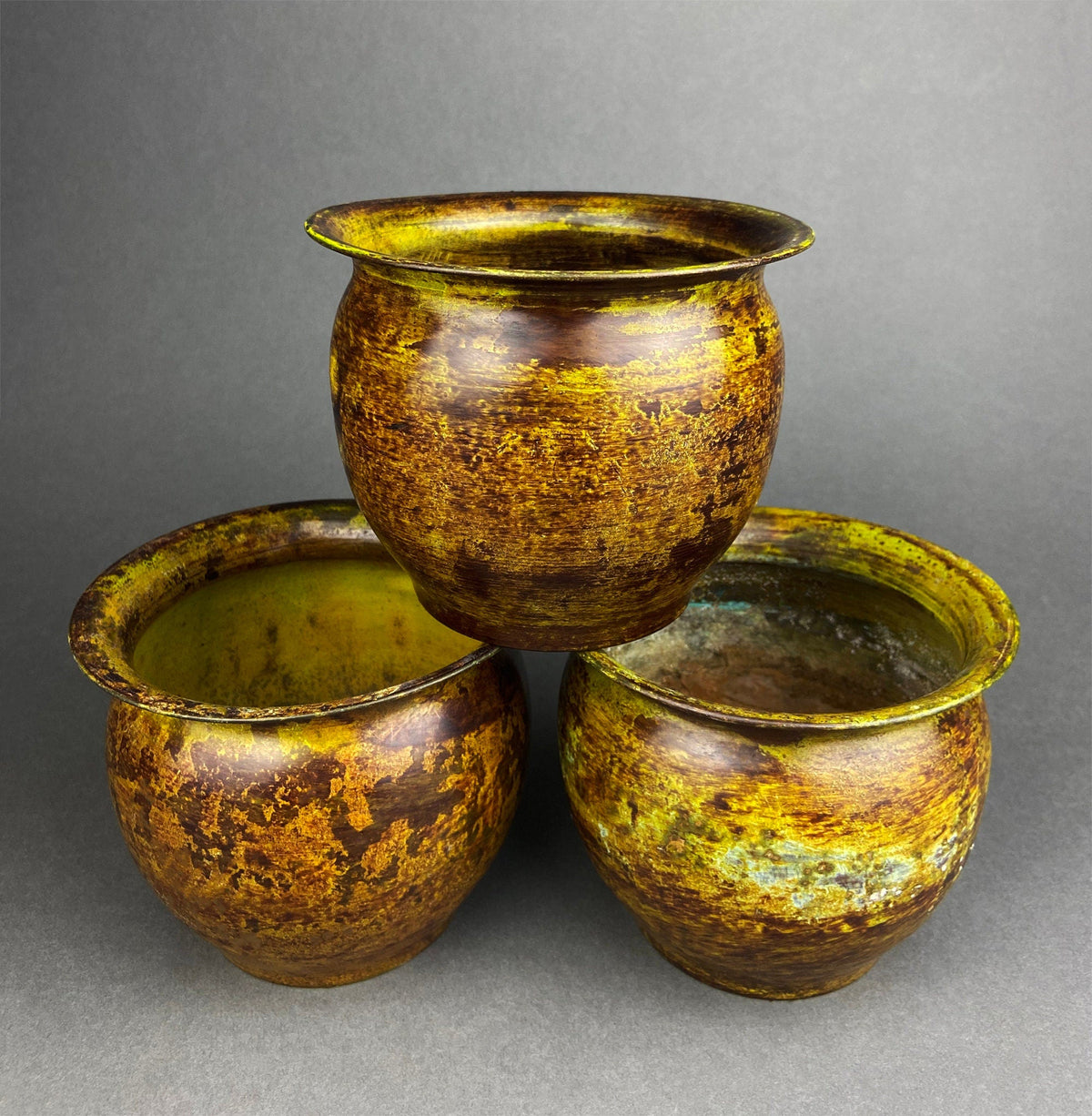 Group of rustic hammered brass flower pot vases with textured green interior