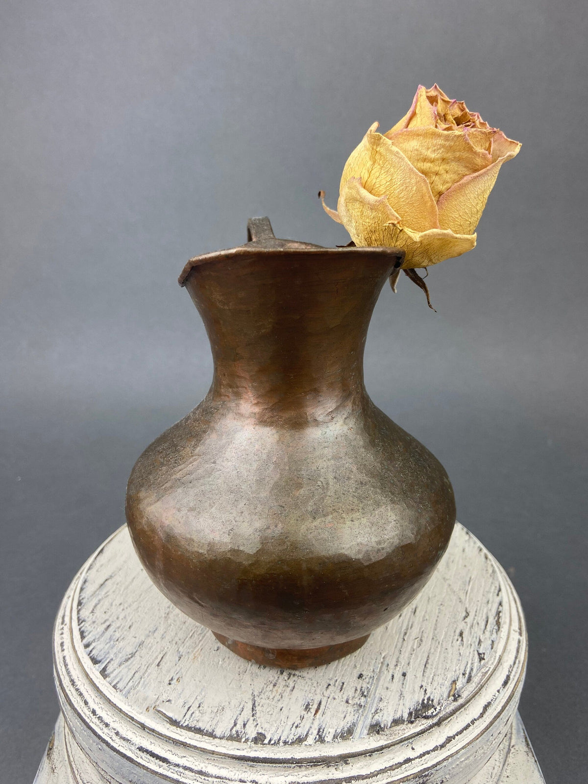 Vintage copper jug with curled spout handle and a rose on the rim