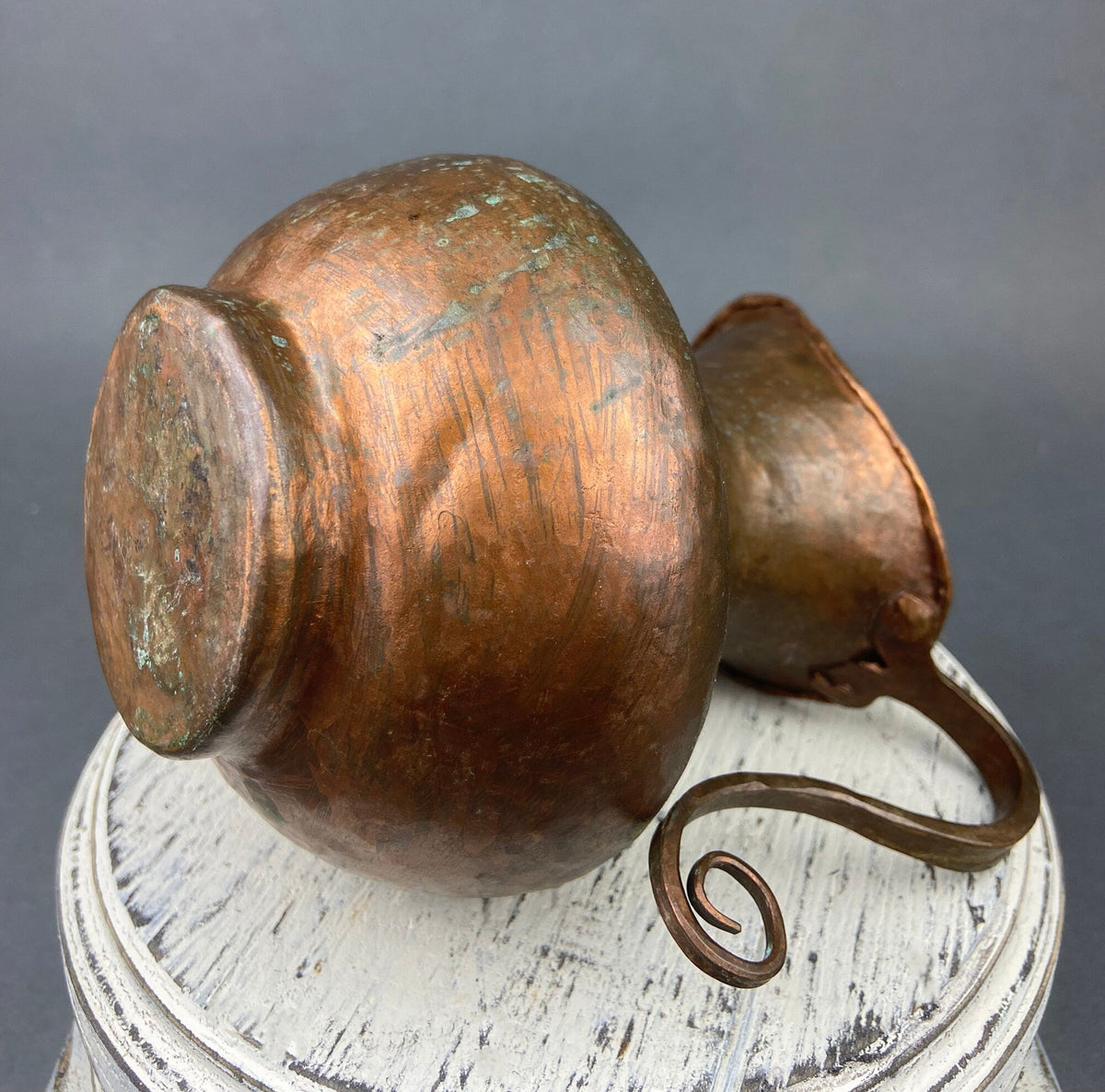 Vintage hammered copper jug with large rounded body, side swirl handle, and patina
