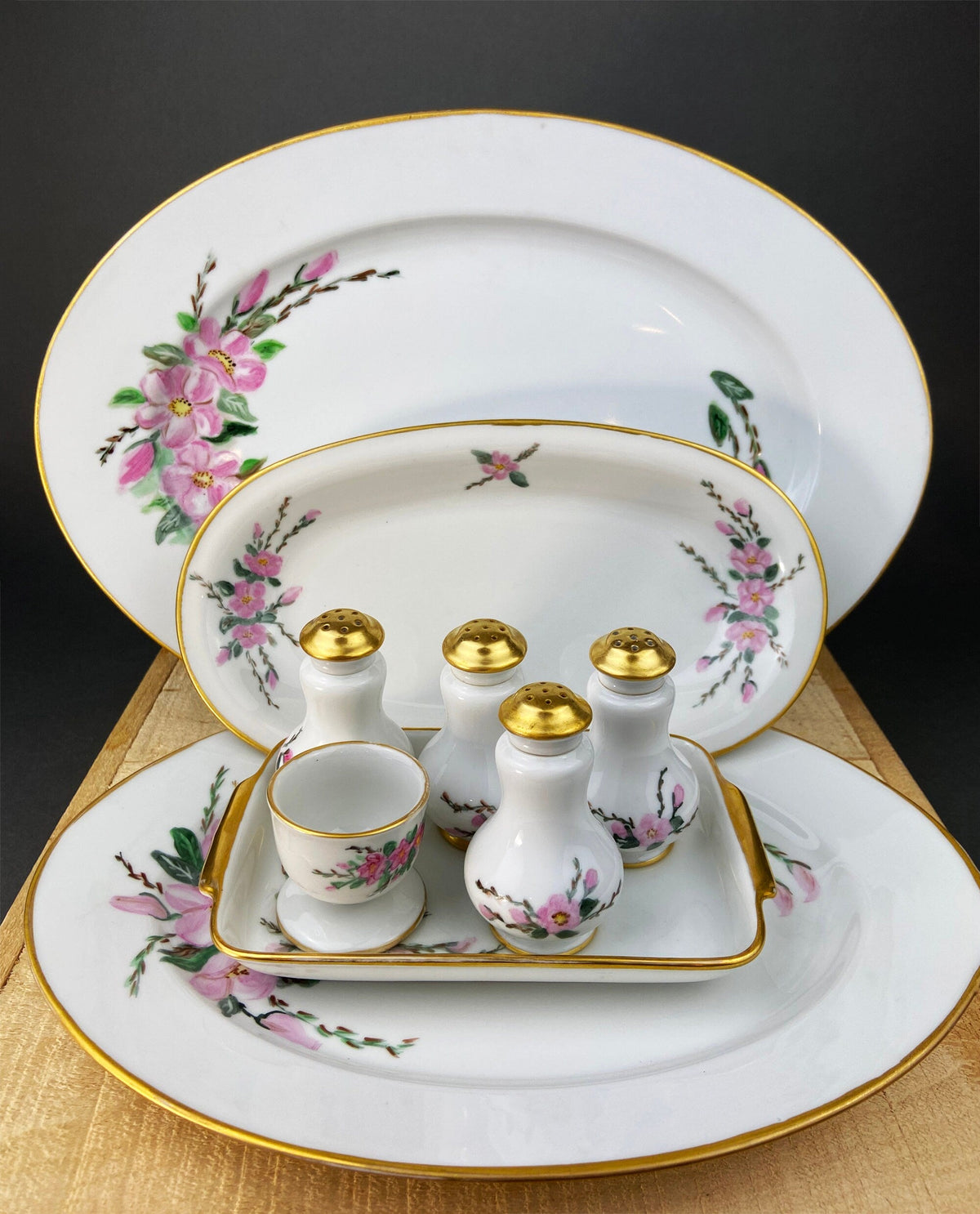 Porcelain oval platter with floral trim, holding egg cup and three spice shakers