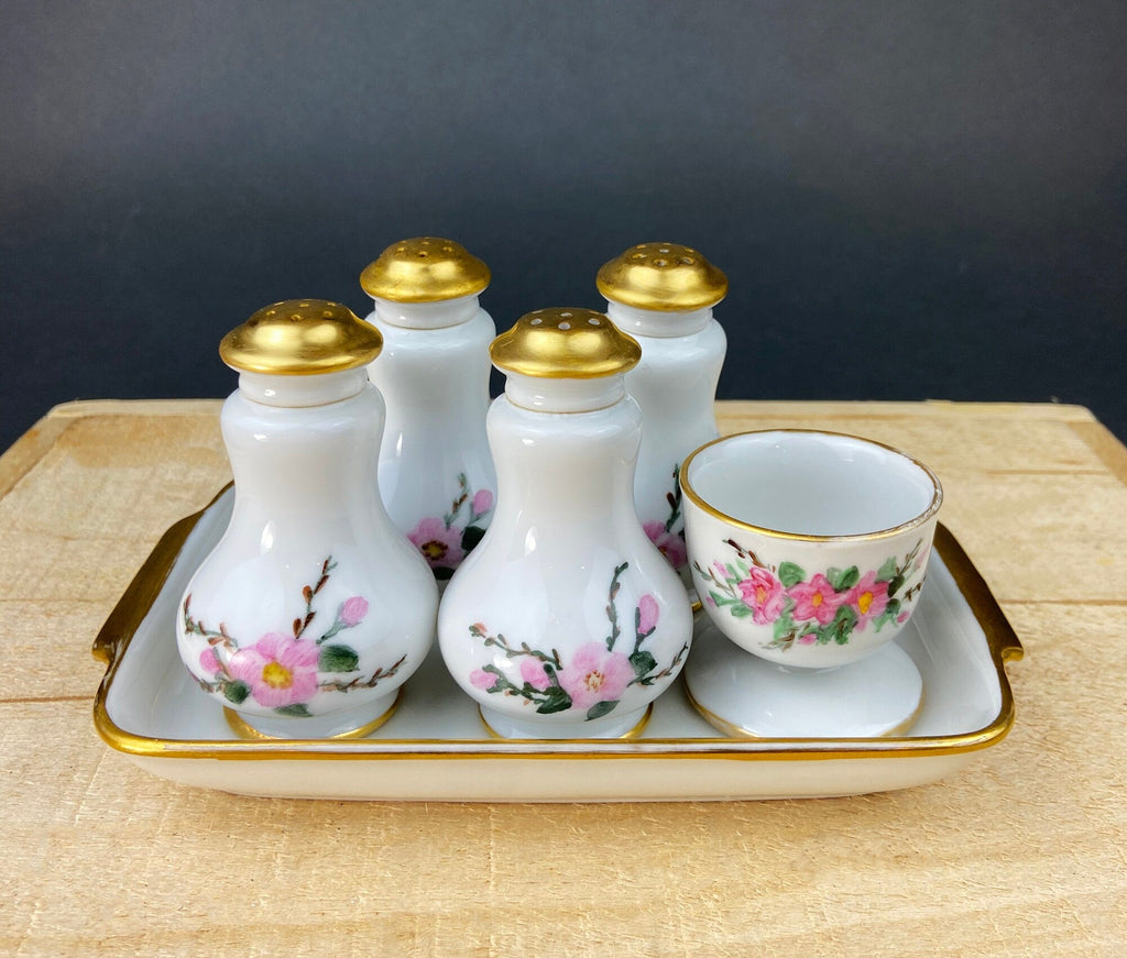 Porcelain spice shaker set with gold tops on rectangular serving tray