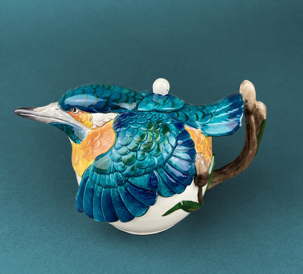 Bird-shaped ceramic teapot with blue scales, white head, and curved handle