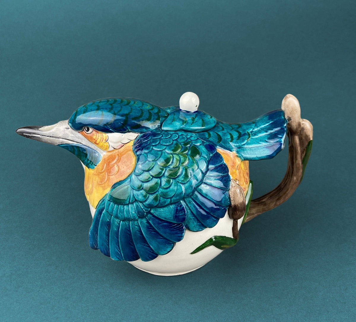 Bird-shaped ceramic teapot with blue scales, white head, and curved handle