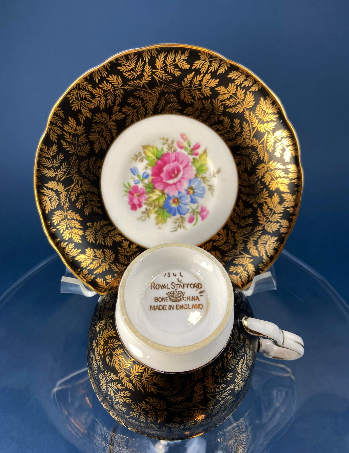 Black cup and saucer with gold leaf pattern; base shows Royal Stafford stamp
