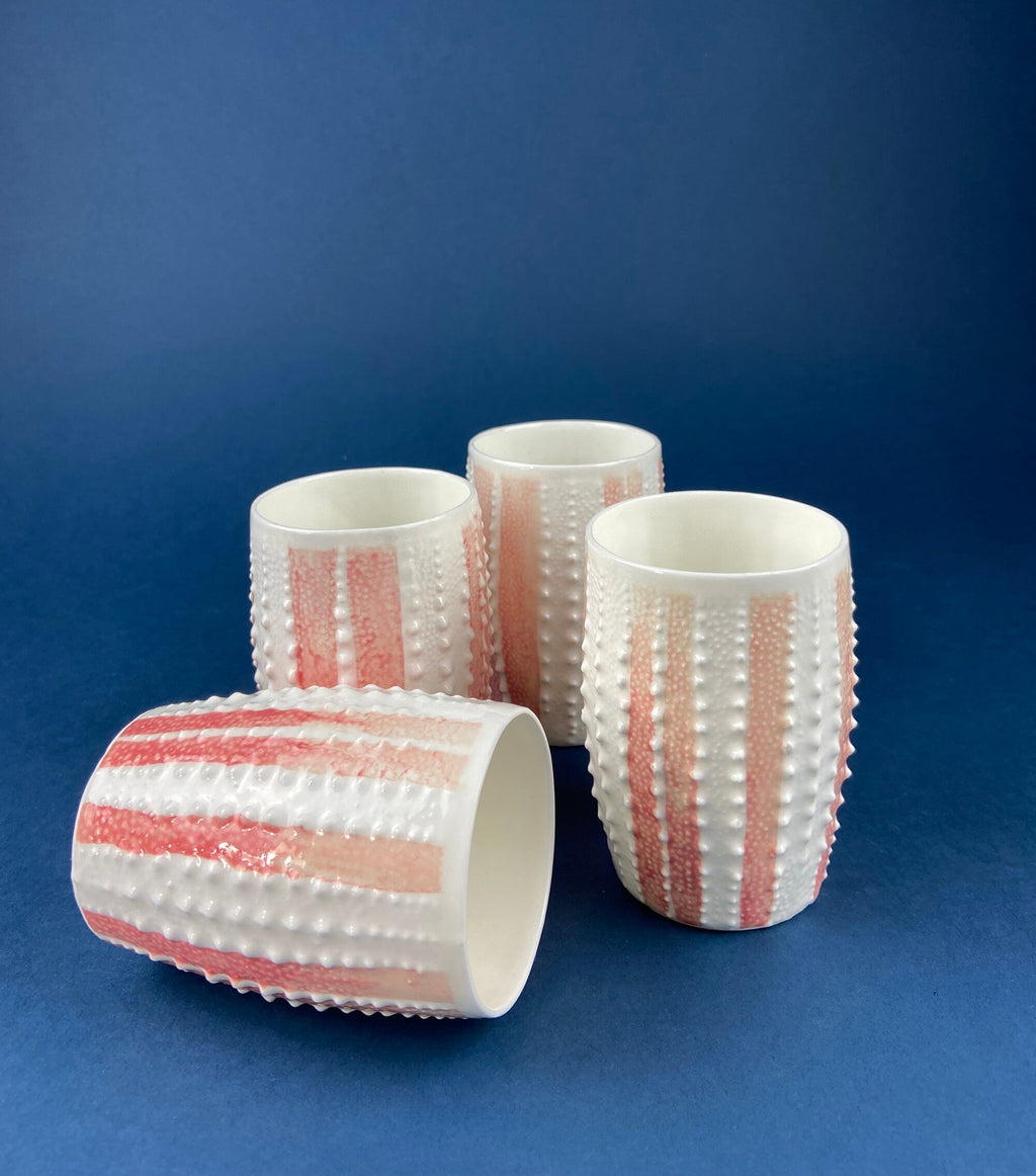 Porcelain mugs with pink vertical stripes and raised dot texture, set of four.