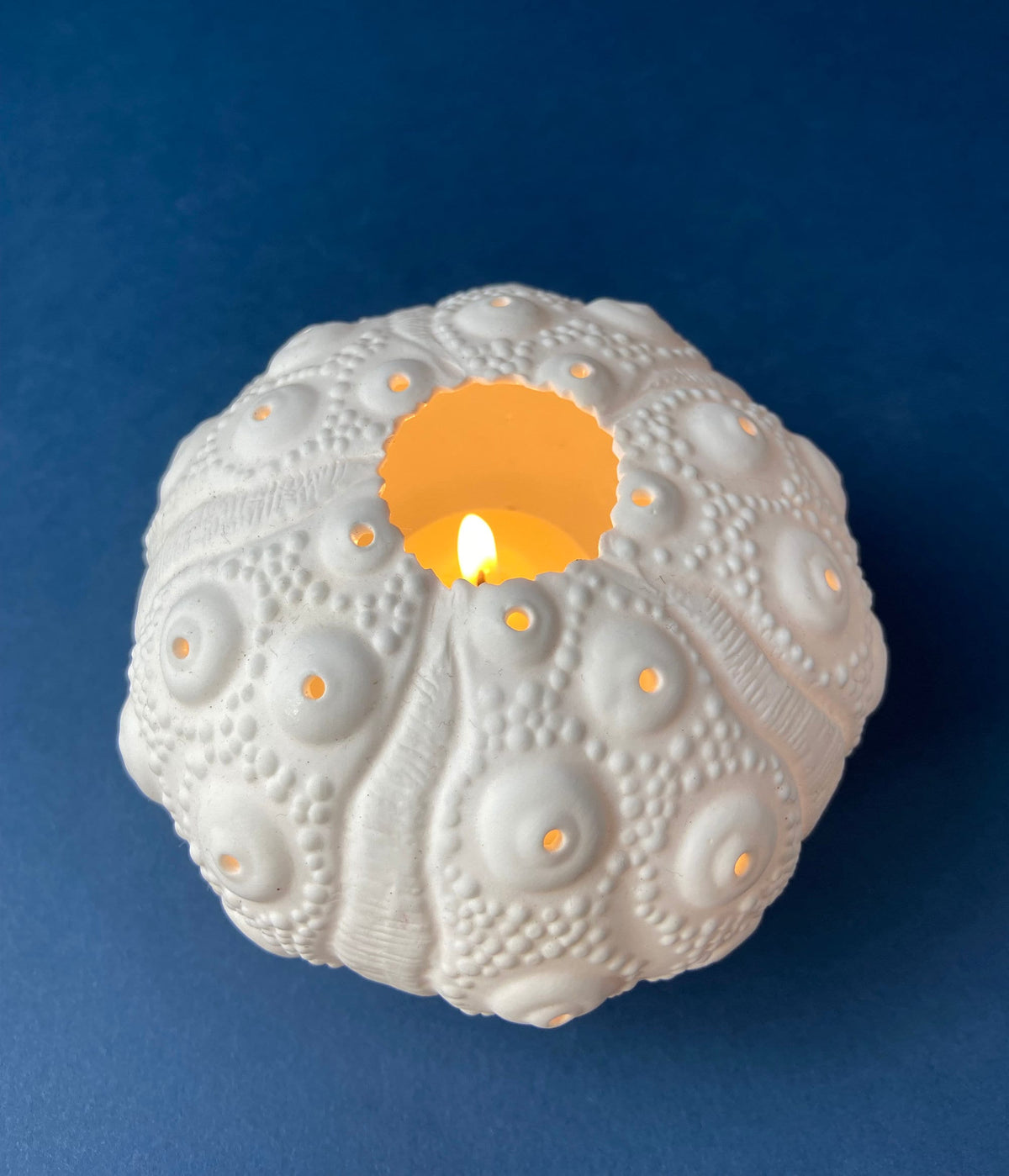 White ceramic bulb with embossed bumps and glowing center opening.